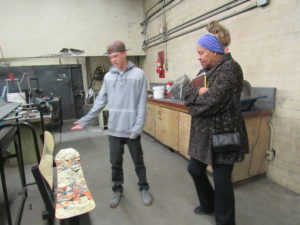 Student, Chase Rigney show Josita Todd a bench made from used snow boards in the welding shop